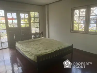 Spacious bedroom with polished hardwood floors and ample natural light streaming through large stained-glass windows, perfect for a serene retreat.