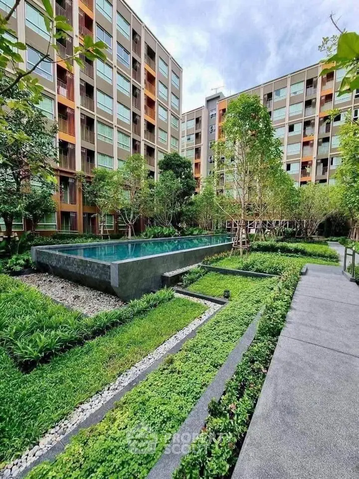 Modern apartment complex with lush garden and sleek pool area, perfect for urban living.