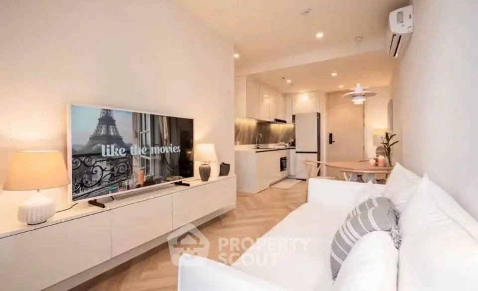 Modern living room with stylish decor and open kitchen layout, featuring a cozy sofa and large TV.
