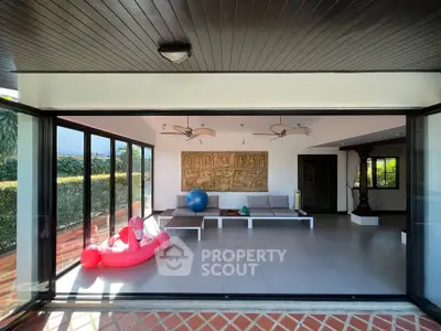 Spacious living room with modern decor and large windows opening to a patio, perfect for relaxation.