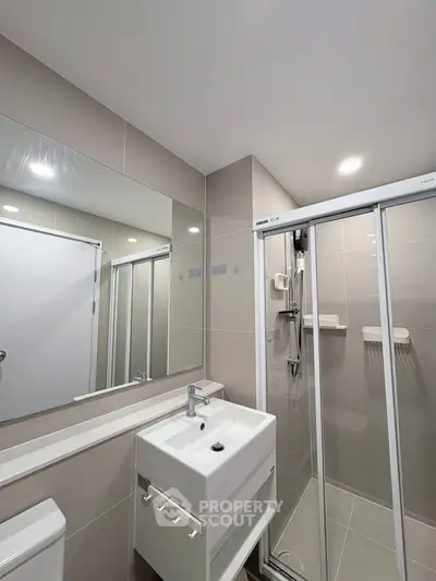 Modern bathroom with sleek shower and stylish sink in contemporary apartment.