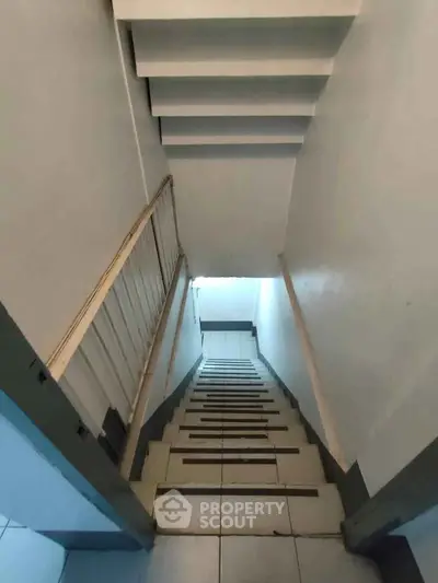 Narrow staircase with tiled steps and white walls in a compact residential setting.