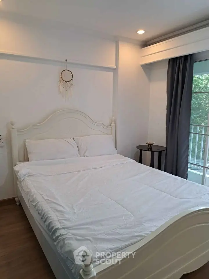 Cozy bedroom with elegant white bed and balcony view, perfect for relaxation.