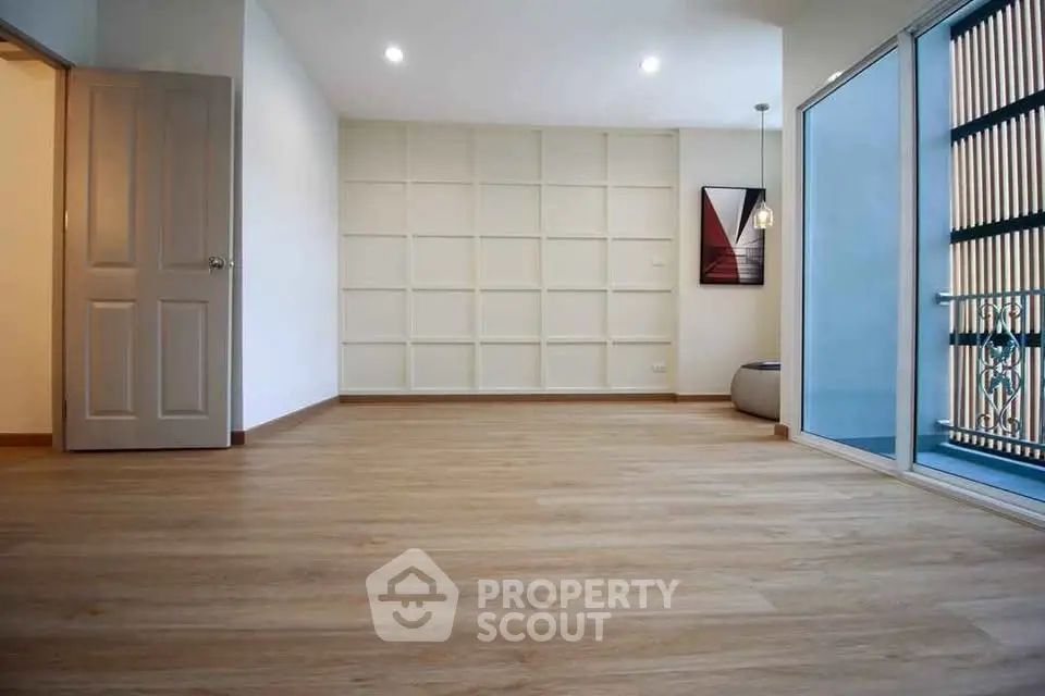 Spacious modern living room with wooden flooring and large windows.