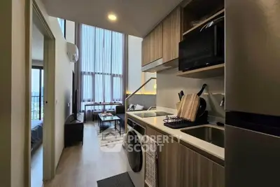 Modern loft apartment with open kitchen and high ceilings, featuring a cozy living area and stylish decor.