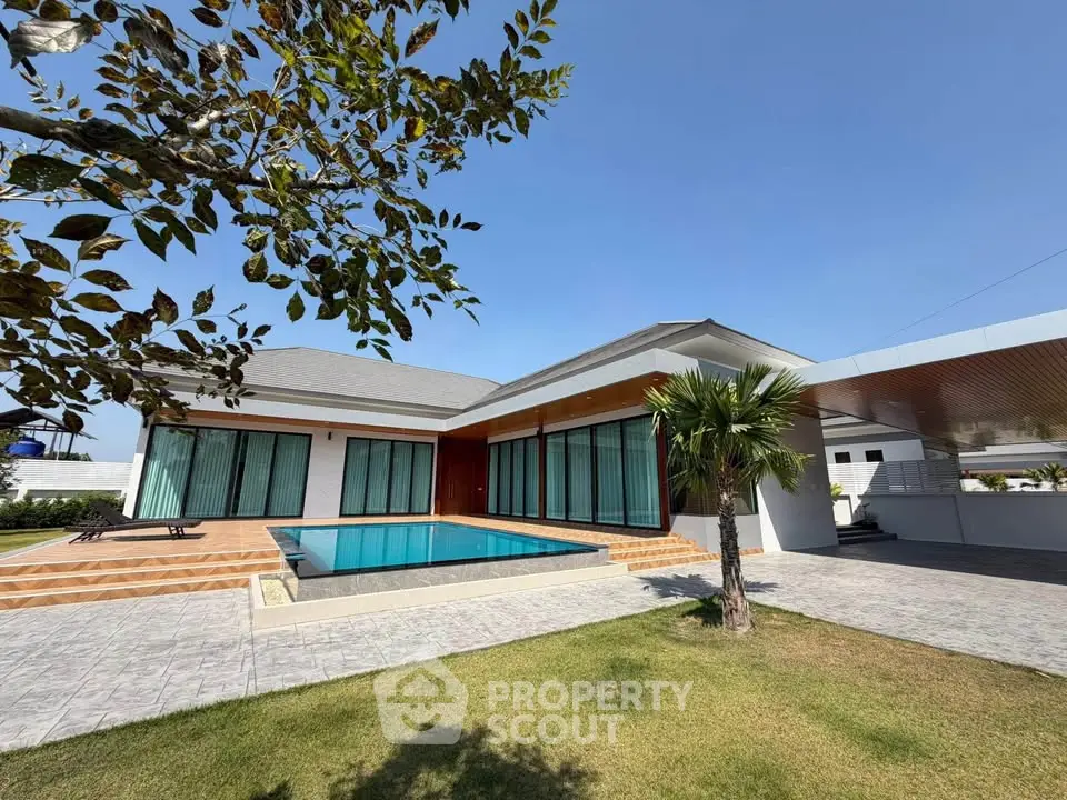 Luxurious modern villa with private pool and spacious garden under clear blue sky.