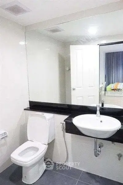 Modern bathroom with sleek fixtures and large mirror in a contemporary home.