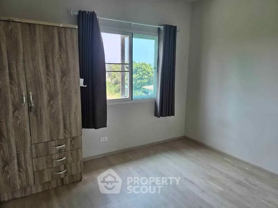 Bright empty bedroom with wooden wardrobe and large window view