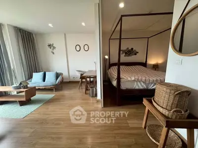 Spacious studio apartment with elegant wooden flooring and cozy bed area