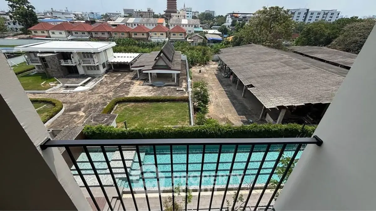 Stunning balcony view overlooking a serene pool and lush garden in a modern residential complex.