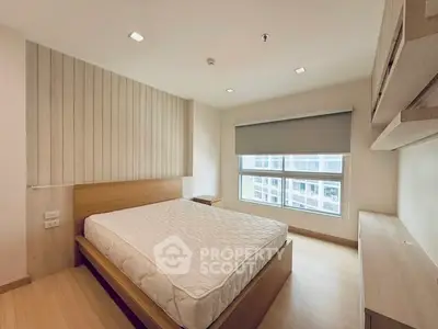 Modern bedroom with wooden flooring and large window in a stylish apartment.