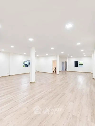 Spacious open-plan interior with modern lighting and wooden flooring, ideal for versatile living or office space.