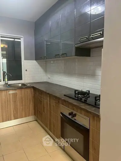 Modern kitchen with sleek cabinets, gas stove, and built-in oven in a stylish apartment.