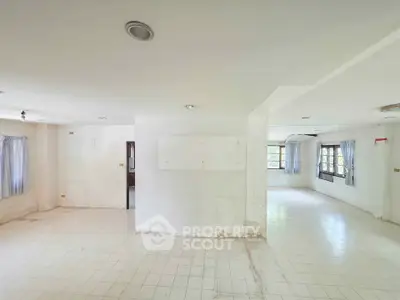 Spacious empty room with tiled flooring and large windows for natural light.