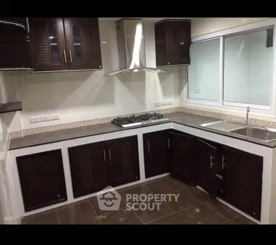 Modern kitchen with dark wood cabinets and gas stove in a sleek corner layout.