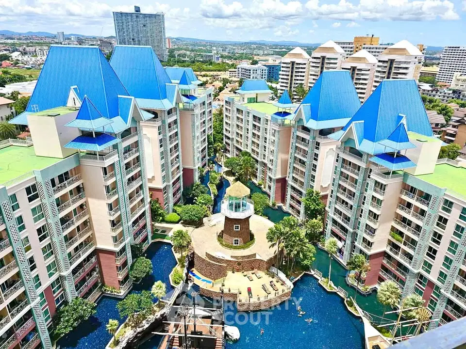 Stunning aerial view of luxurious condominium complex with vibrant blue roofs and lush landscaping.