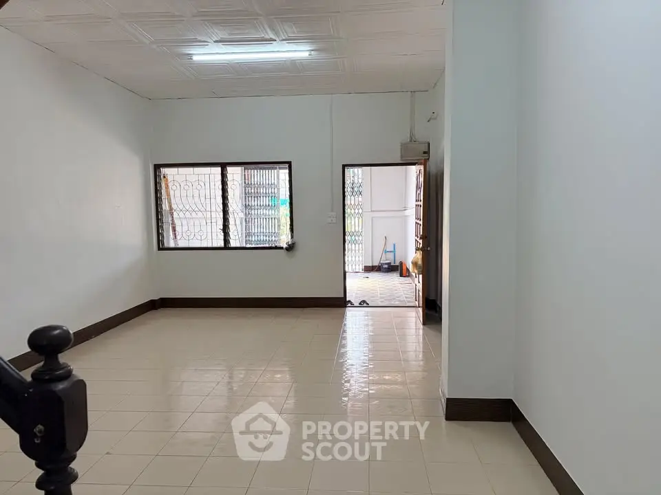 Spacious empty living room with tiled floor and large windows, perfect for customization.