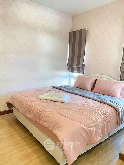 Cozy bedroom with pink bedding and floral wallpaper, perfect for relaxation.