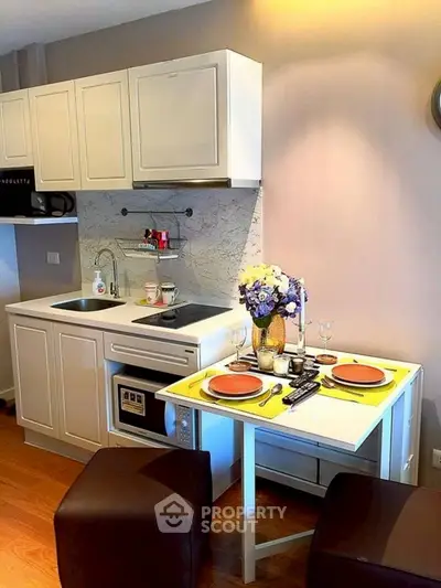Charming compact kitchen with dining area, featuring modern appliances and elegant decor.
