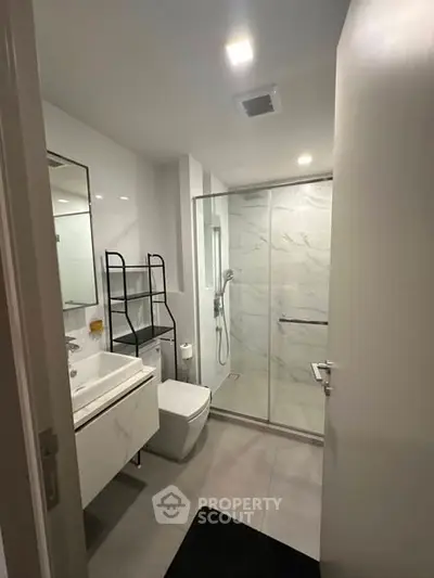 Modern bathroom with glass shower and sleek fixtures in a contemporary apartment.