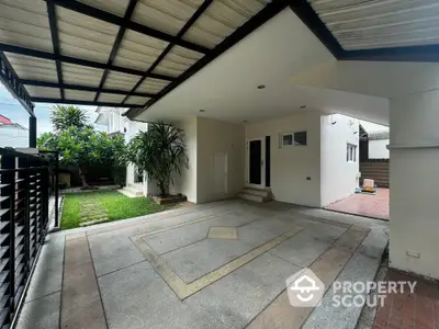 Spacious modern home entrance with covered driveway and lush garden