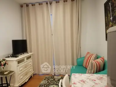 Cozy living room with elegant decor, featuring a TV, stylish sofa, and floral accents, perfect for relaxation.