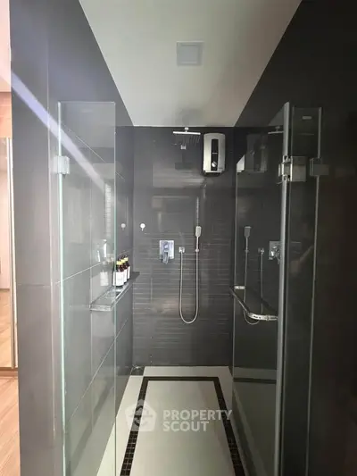 Modern bathroom with sleek glass shower doors and dark tile design