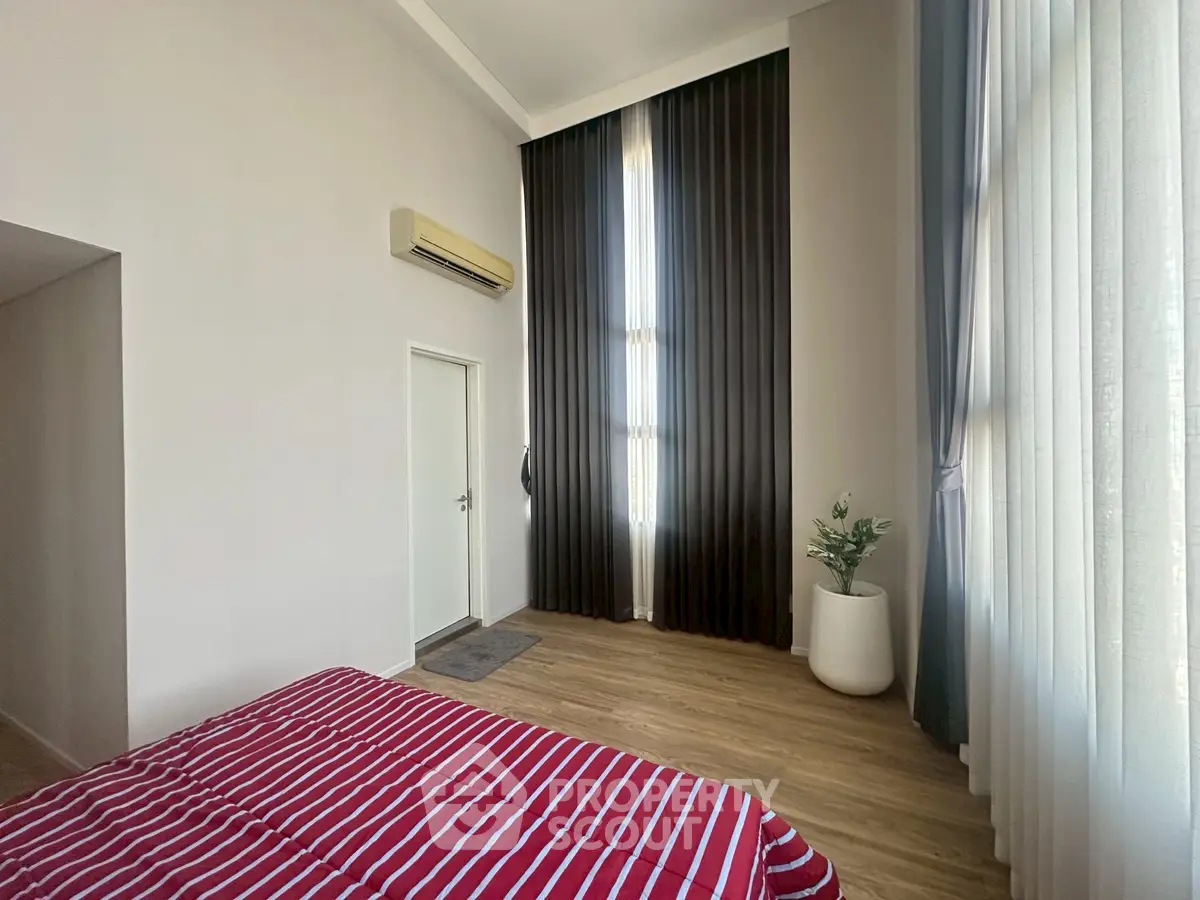 Spacious bedroom with high ceilings and elegant floor-to-ceiling curtains