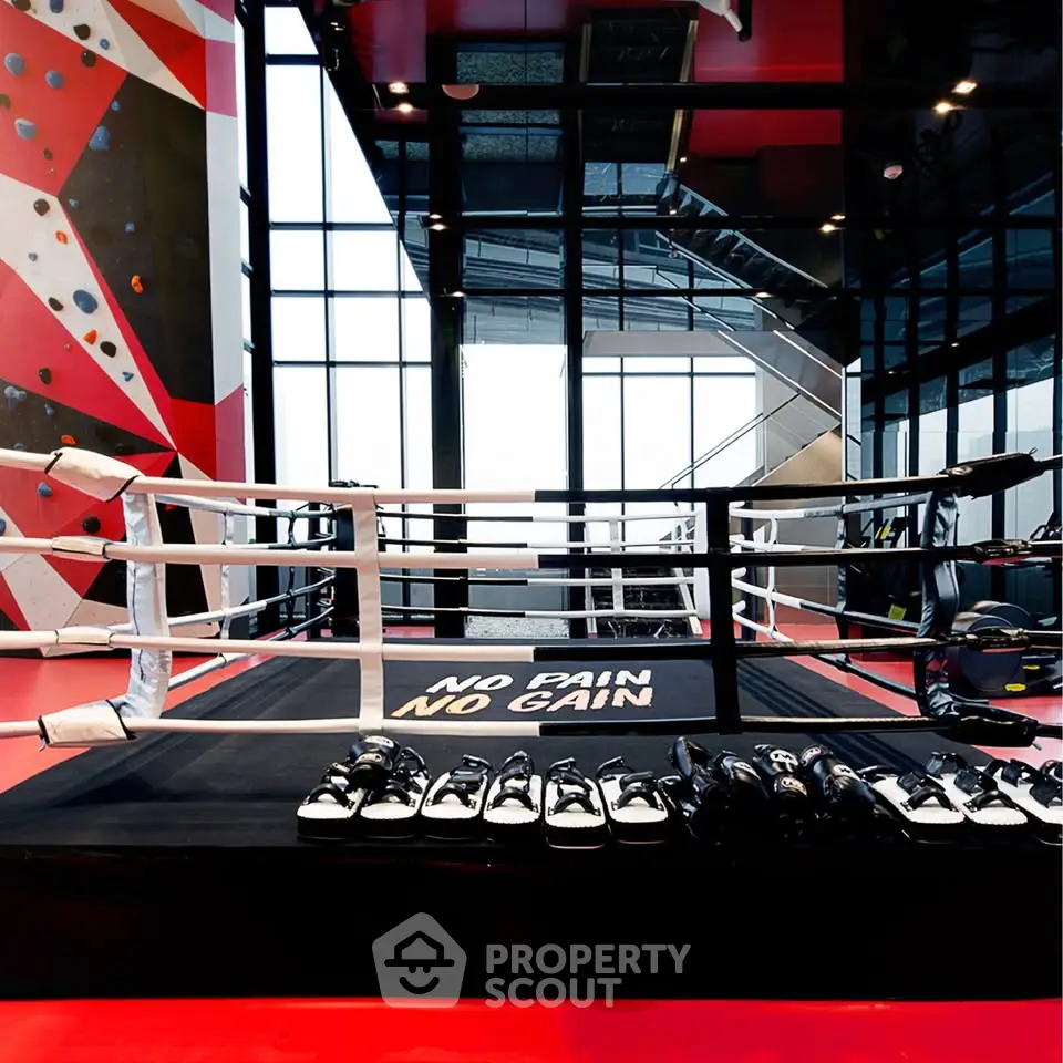 Modern gym with boxing ring and climbing wall, featuring sleek design and motivational decor.