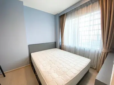 Bright and cozy bedroom with large window and modern decor, perfect for relaxation.