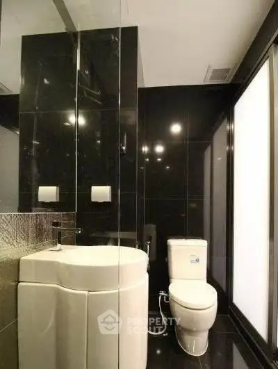 Modern bathroom with sleek black tiles and contemporary fixtures.