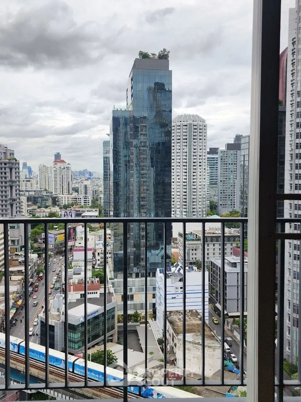 Stunning cityscape view from a high-rise balcony overlooking modern skyscrapers and bustling streets.