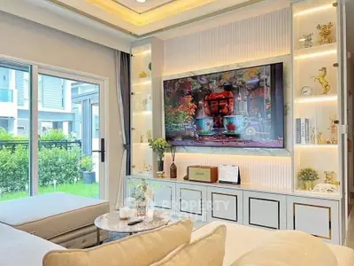 Luxurious living room with modern decor and large TV, overlooking a lush garden.