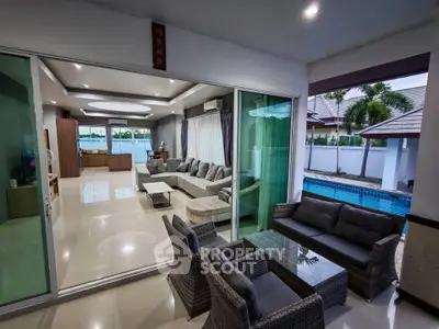 Luxurious open-plan living room with pool view and modern furnishings in a tropical villa.