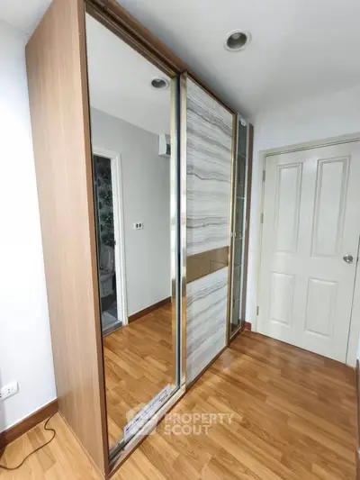 Modern bedroom with sleek wooden flooring and stylish sliding wardrobe doors.