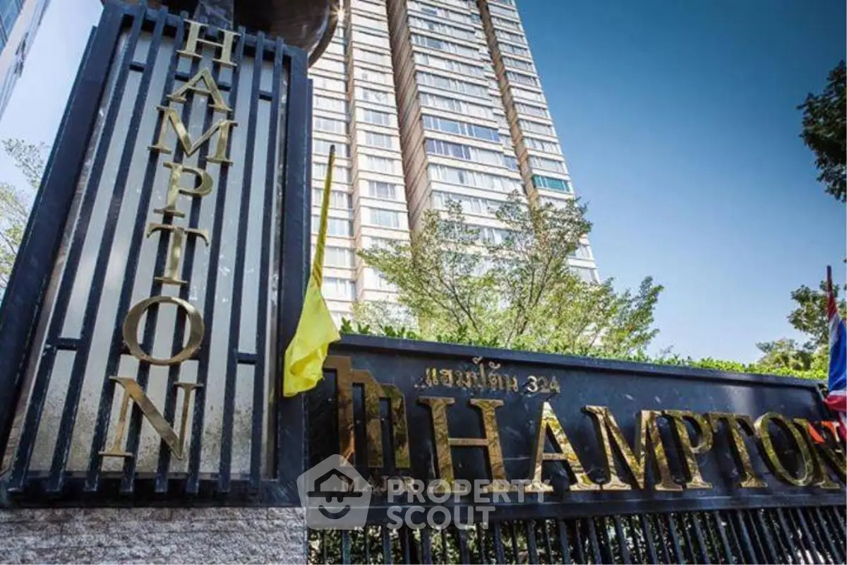 Luxurious high-rise building entrance with elegant signage and lush greenery.
