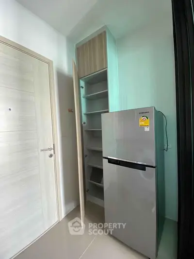 Modern kitchen corner with sleek fridge and built-in storage shelves