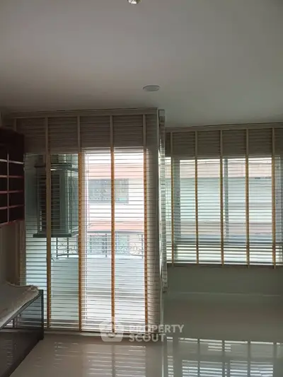 Modern living room with large windows and stylish blinds, offering ample natural light and a sleek design.