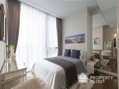 Elegantly designed bedroom with plush bedding, hardwood floors, and a seamless transition to a chic living area, enhanced by natural light from floor-to-ceiling windows.