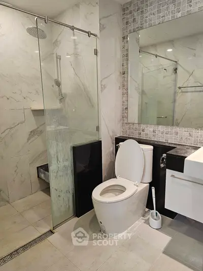 Modern bathroom with glass shower and sleek fixtures in luxury apartment.