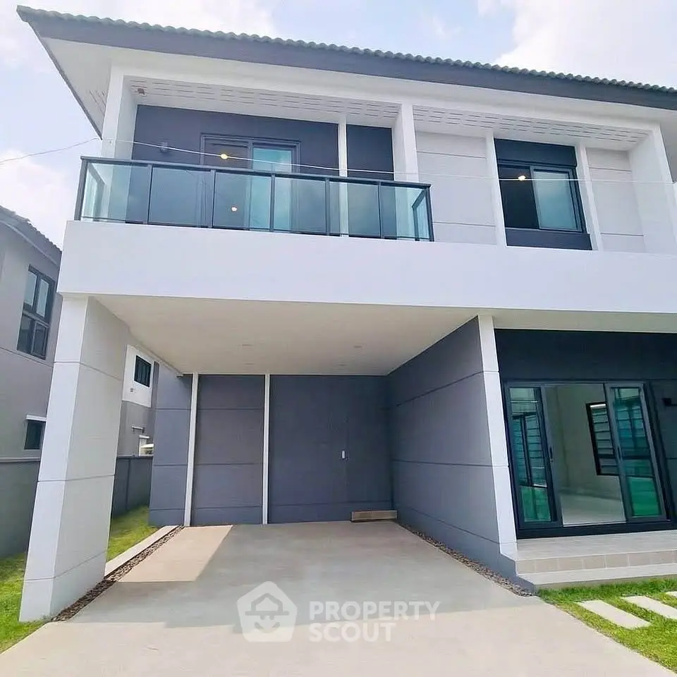 Modern two-story house with spacious balcony and driveway in a serene neighborhood.