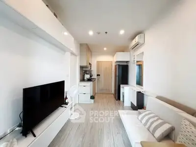 Modern living room with sleek design, featuring a large TV, stylish furniture, and open kitchen layout.