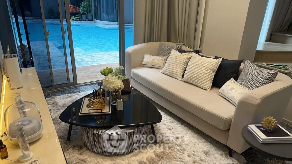 Luxurious living room with pool view, elegant decor, and cozy seating area.