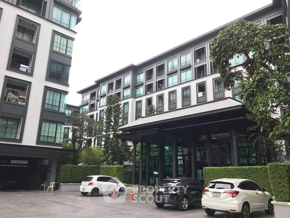 Modern residential building with parking area and lush greenery, showcasing urban living convenience.