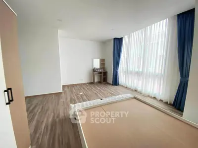 Spacious bedroom with large windows and wooden flooring, perfect for natural light lovers.