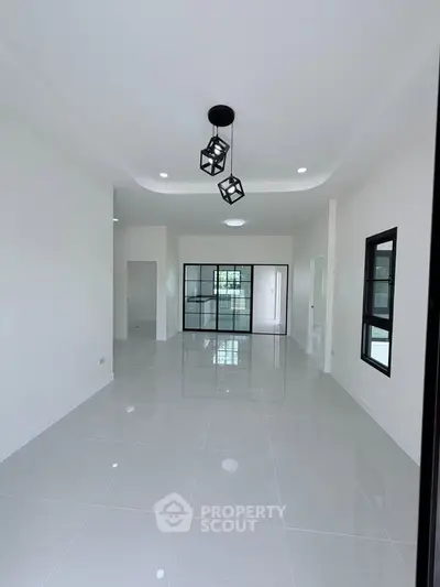 Spacious modern living room with sleek tile flooring and stylish lighting fixtures.