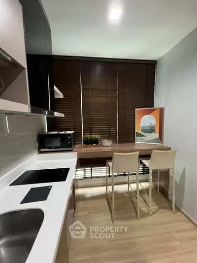 Modern kitchen with sleek design, featuring induction cooktop and cozy dining area.