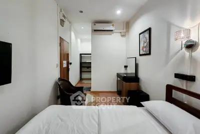 Cozy bedroom with modern decor and air conditioning, featuring a sleek vanity and comfortable seating.