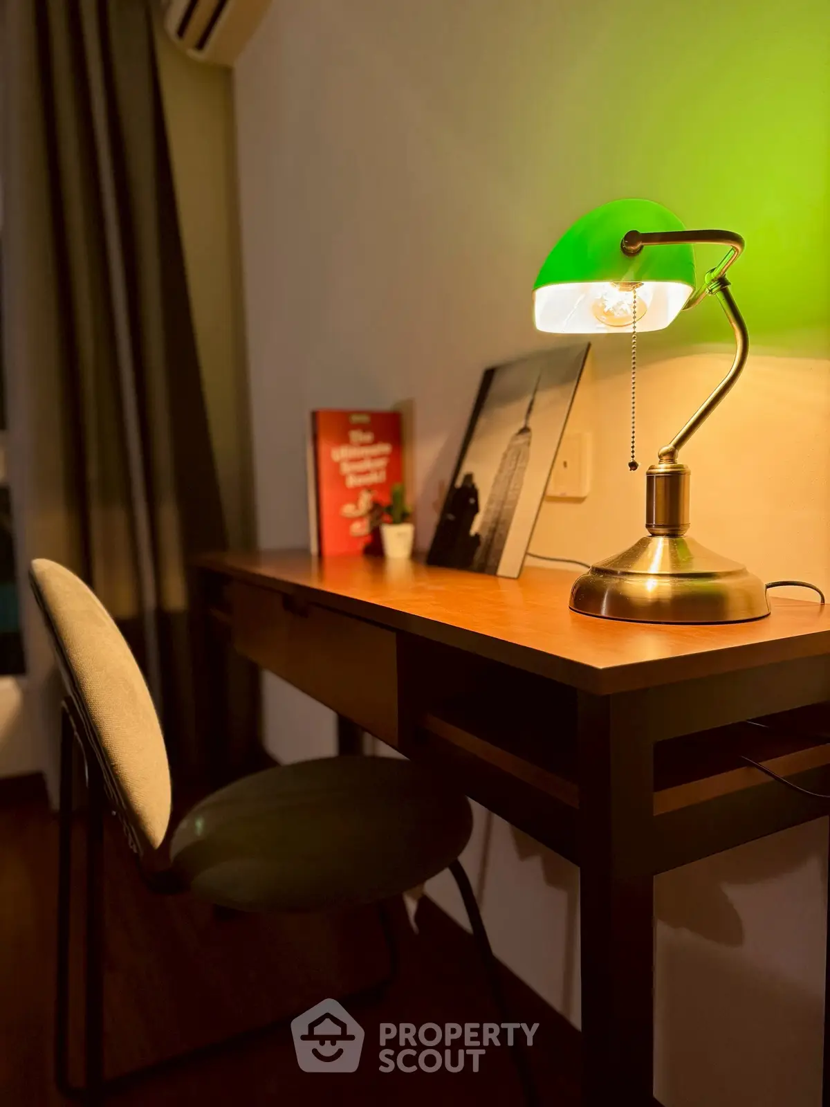 Cozy study area with elegant desk lamp and comfortable chair, perfect for focused work.