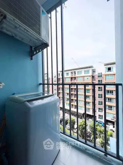 Compact balcony with washing machine and city view, ideal for urban living convenience.